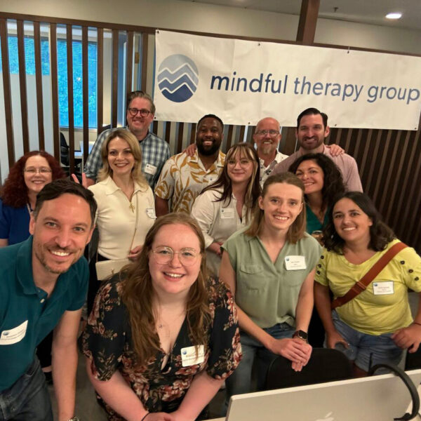 Mindful Therapy Group staff pose in front of a company banner