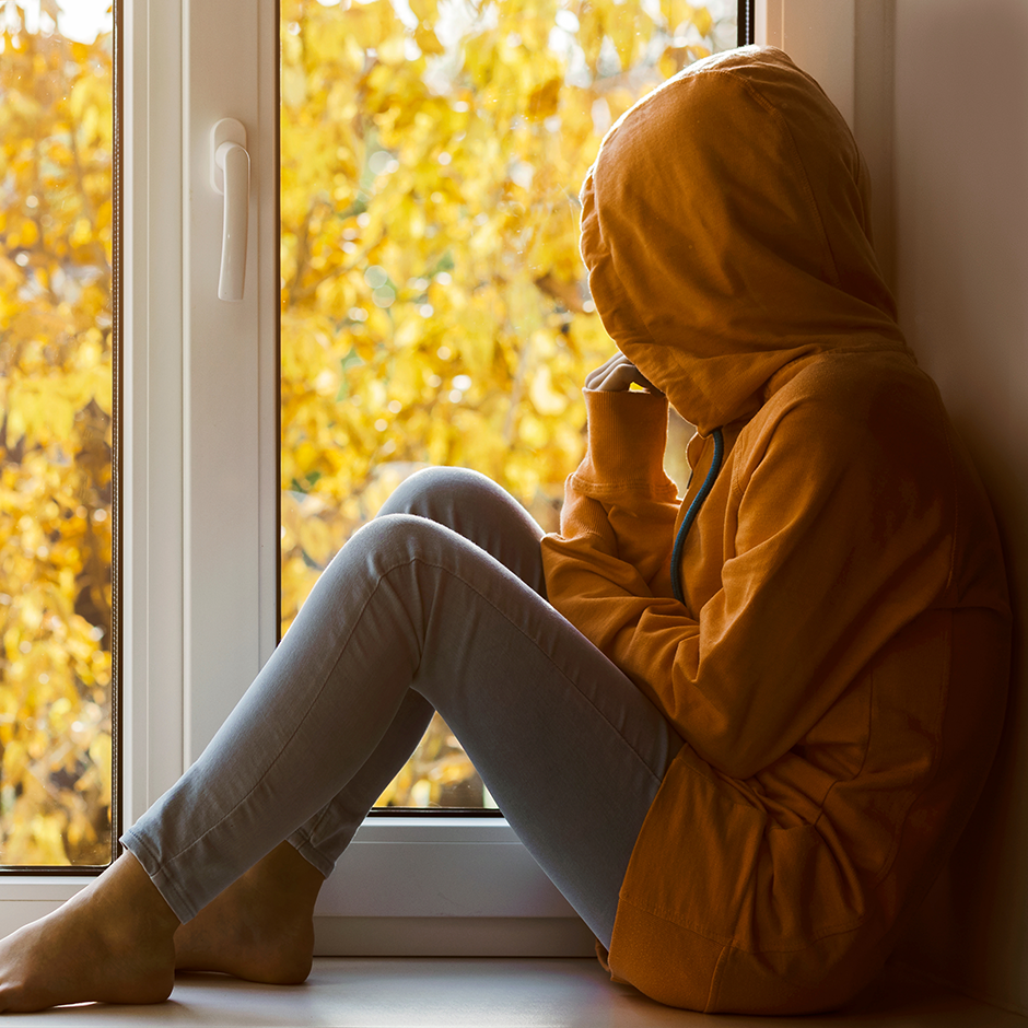 Person looking out at Autumn landscape sad