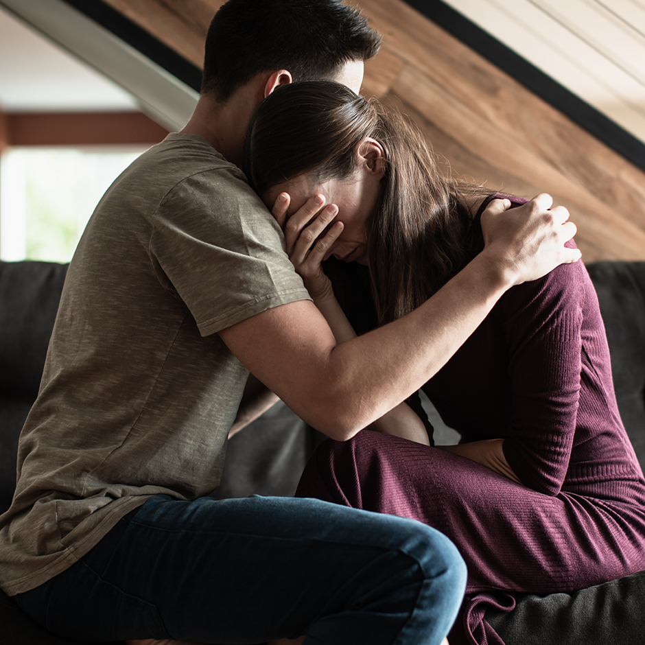 man comforting and hugging woman while she is crying
