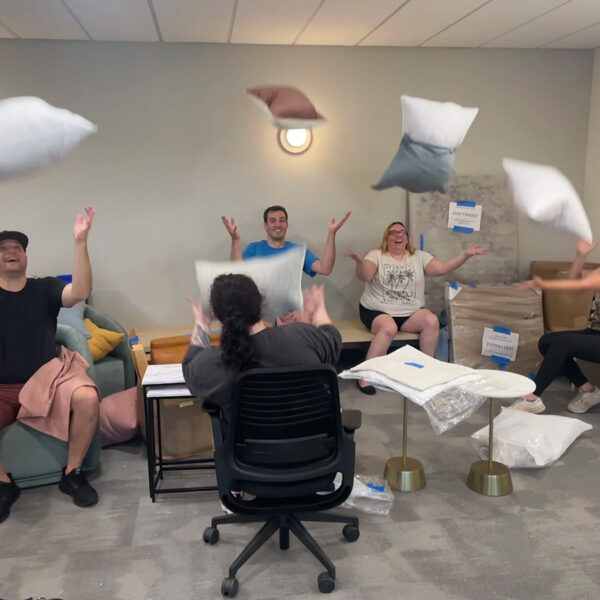 Mindful Support Services staff celebrate by throwing pillows in the air in unison