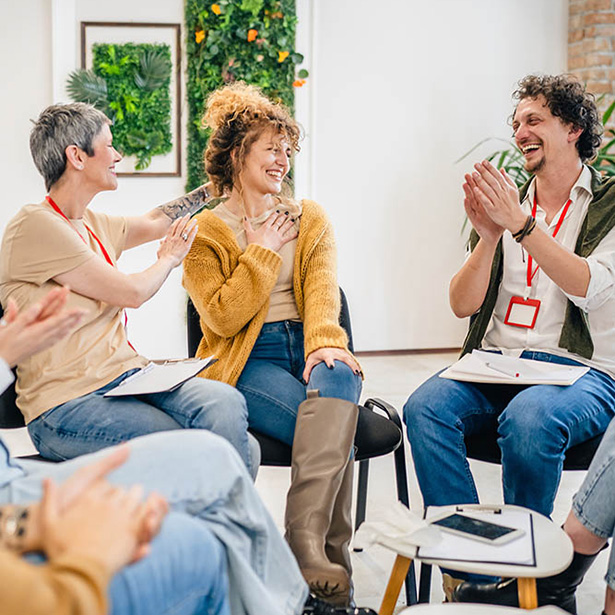 A group of people sit in a circle, engaging in a therapy session