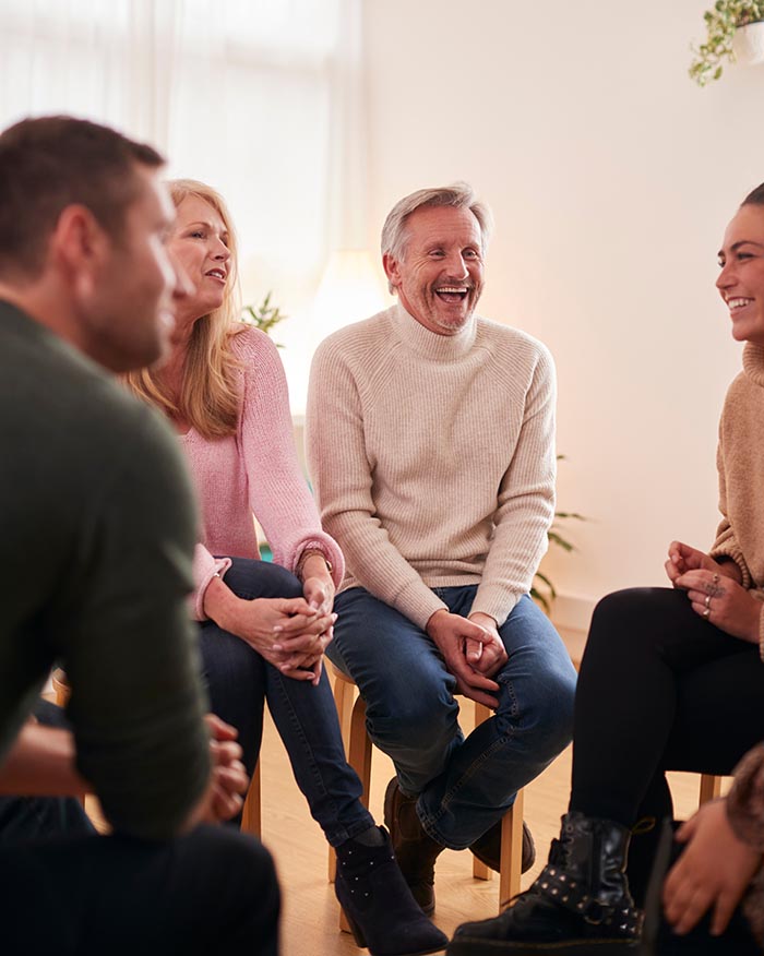 A group of people sit in a circle, engaging in a therapy session